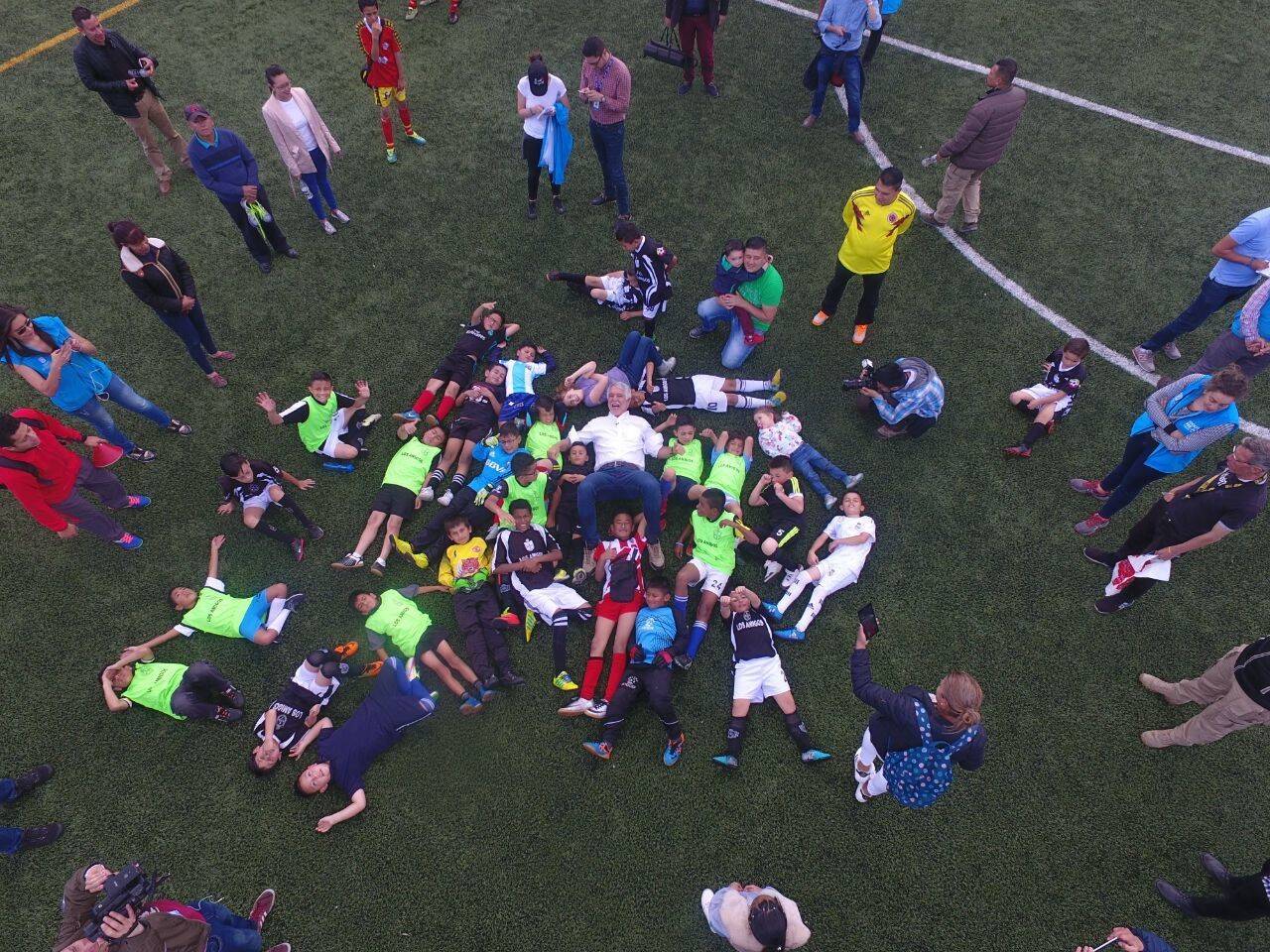 Alcalde Peñalosa acostado junto a niños en cancha sintética
