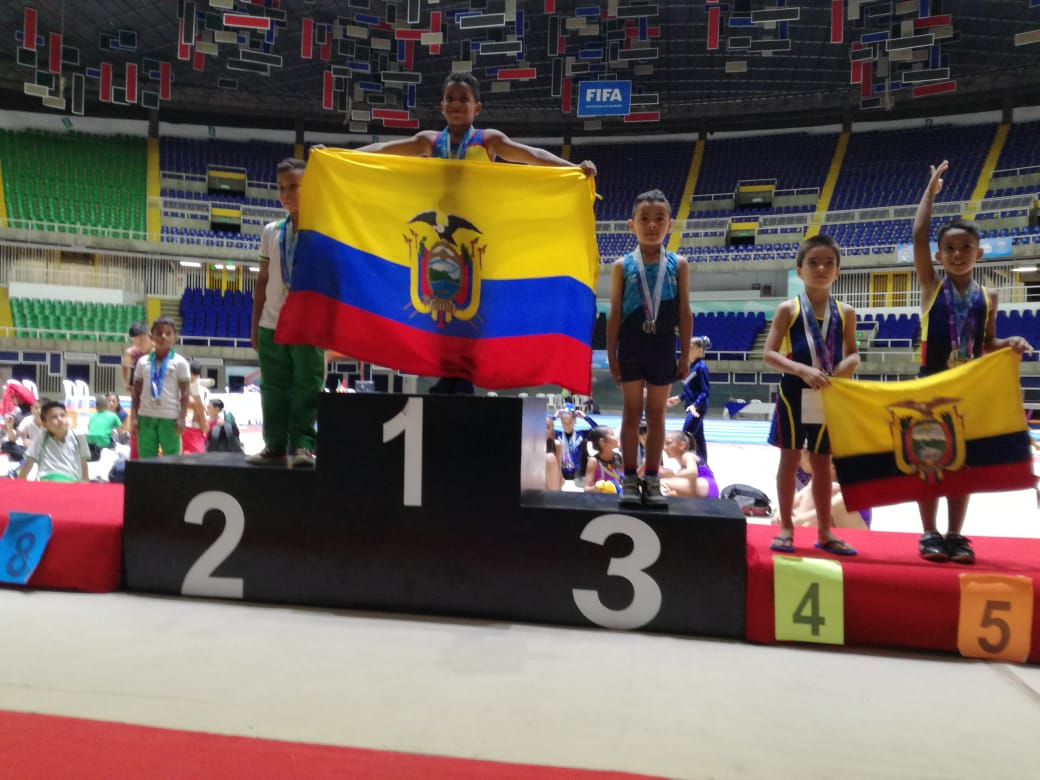 Niños deportistas sostienen bandera de Colombia en el podio