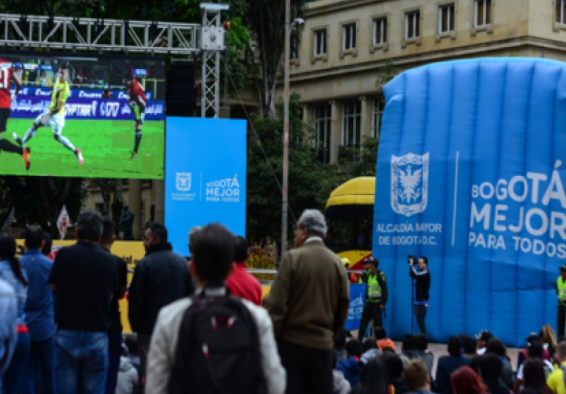Personas ven partido de fútbol en pantalla gigante
