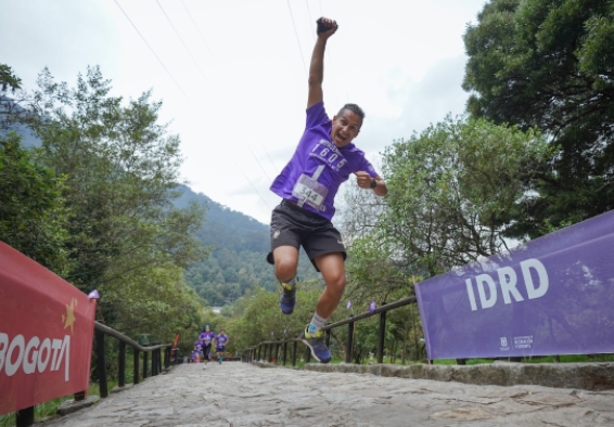 Un hombre saltando con un brazo arriba en el sendero peatonal de Monserrate