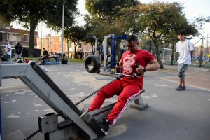 Hombres usando las maquinas de un gimnasio en un parque