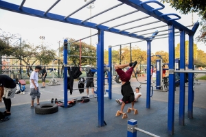 Varias personas usando las maquinas de un gimnasio en un parque