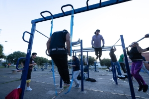Varias personas usando las maquinas de un gimnasio en un parque