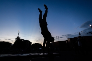 Silueta a contra luz de un hombre usando las maquinas de un gimnasio en un parque