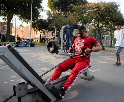 Hombres usando las maquinas de un gimnasio en un parque