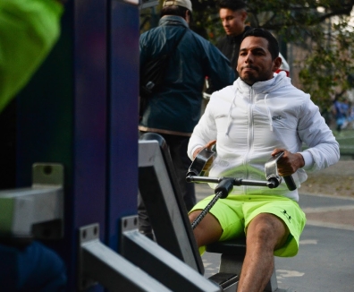 Hombres usando las maquinas de un gimnasio en un parque