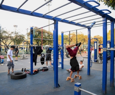 Varias personas usando las maquinas de un gimnasio en un parque