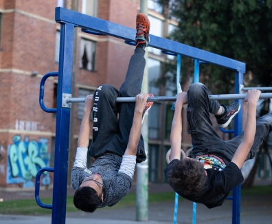 2 hombres usando las maquinas de un gimnasio en un parque