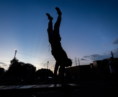 Silueta a contra luz de un hombre usando las maquinas de un gimnasio en un parque
