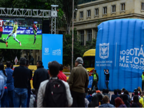Personas ven partido de fútbol en pantalla gigante