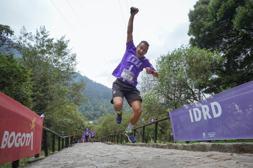 Un hombre saltando con un brazo arriba en el sendero peatonal de Monserrate