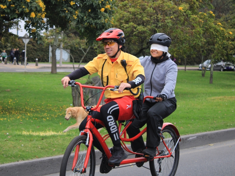 Guardián en bicicleta tandem llevando a persona con los ojos cubiertos