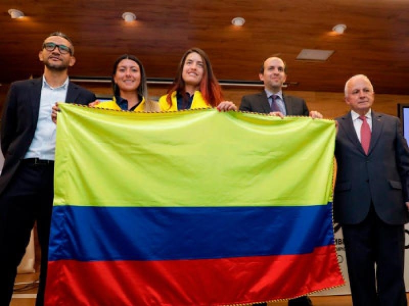 Deportistas y representantes de la delegación sostienen bandera