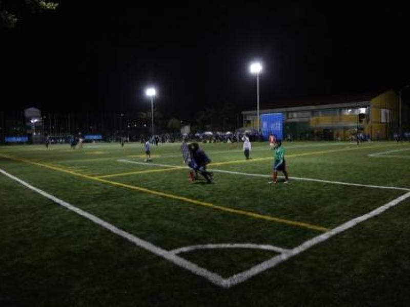 Niños juegan en cancha de fútbol en la noche