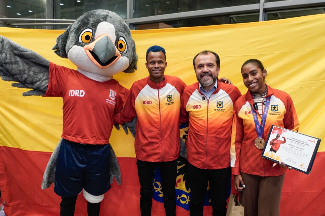 Carlos Sanmartín (izq.) con el director del IDRD, Daniel García Cañón, y Natalia Linares, a su llegada a Bogotá. Con ellos, Xue, una de las mascotas de la escuadra capitalina. Foto IDRD.